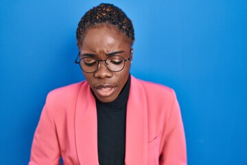 Fototapeta premium Beautiful black woman standing over blue background with hand on stomach because nausea, painful disease feeling unwell. ache concept.