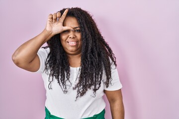 Plus size hispanic woman standing over pink background making fun of people with fingers on forehead doing loser gesture mocking and insulting. - obrazy, fototapety, plakaty