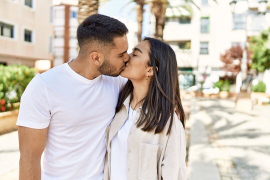 Young latin couple kissing and hugging standing at the city.