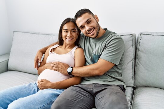 Latin man and woman couple hugging each other expecting baby at home
