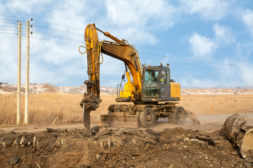 A working excavator with attachments on the construction of a road junction.