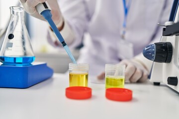 Fototapeta premium Young hispanic man scientist using pipette working at laboratory