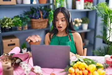 Brunette woman working at florist shop doing video call scared and amazed with open mouth for surprise, disbelief face