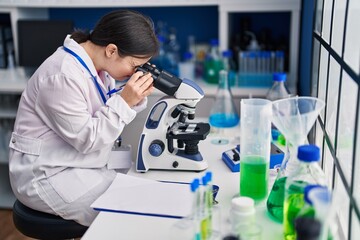 Fototapeta premium Young woman with down syndrome scientist using microscope at laboratory