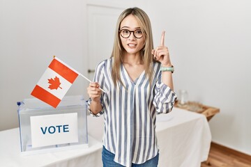 Asian young woman at political campaign election holding canada flag surprised with an idea or...
