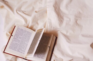 Open book on the bed flat lay stock photography. Warm and cozy atmosphere. Home aesthetic