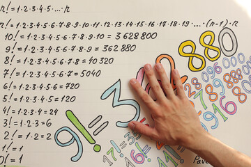 Young man hand and colourful numbers on the paper. Pavel Kubarkov, my right hand and factorial numbers. Photo was taken 27 July 2022 year, MSK time in Russia. - 534805934