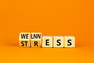 Stress or wellness symbol. Concept words Stress or Wellness on wooden cubes. Beautiful orange table orange background. Business stress or wellness concept. Copy space.