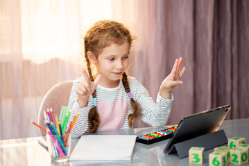 An elementary school girl learns mental arithmetic online from home. Education.