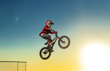 A teenager BMX Racing Rider performs tricks in a skate park on a pump track.