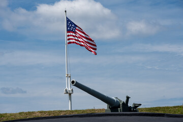 A gun battery with an old American flag in the background from Fort Moultrie 
