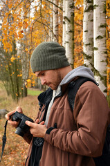 young man with camera in autumn forest