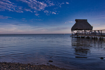 sunset over the sea with bungalow against sky