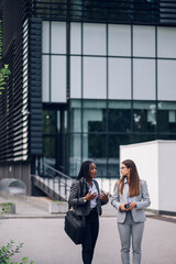 Two multiracial business woman meeting outside and using a smartphone