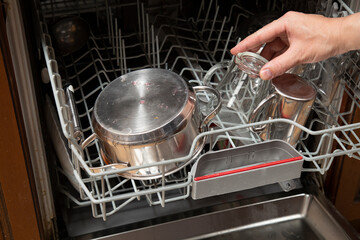 A man puts dirty dishes in the dishwasher.Household work in the kitchen.