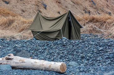 An old canvas tent after storm on rocky seashore.