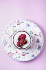 Milk yogurt with raspberries in a bowl on a pink background 