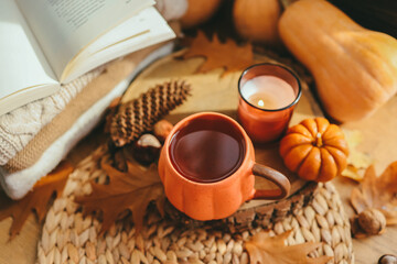 A cup of tea in the shape of a pumpkin and autumn decor on the windowsill, aesthetic photo.