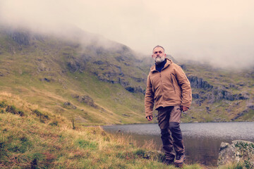 Bearded Man reaching the destination  alone to  the lake in  mountains on foggy autumn day  Travel  Lifestyle concept The national park Lake District in England