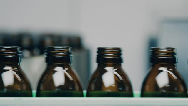 4K Conveyor with empty glass vials for medical injections on the production line. Modern High-Tech Pharmacology Factory, Moving Production Line. Pharmaceutical Manufacturing. Macro, DOF