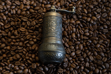 Old coffee grinder with coffee beans in the background