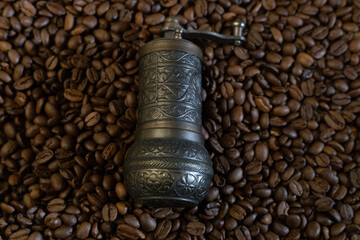 Old coffee grinder with coffee beans in the background