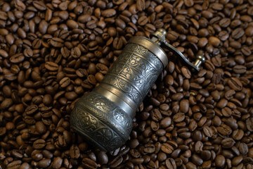 Old coffee grinder with coffee beans in the background