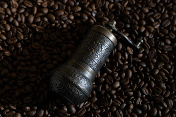 Old coffee grinder with coffee beans in the background