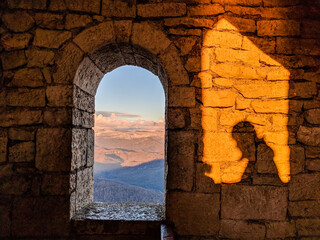Mountains view through the window in old tower with man shadow on the wall