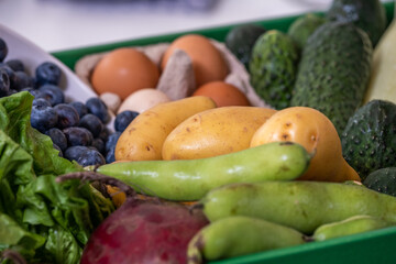 green box with vegetables, beets, potatoes, cucumbers in kitchen with white blurred background, kitchen poster, food advertisement