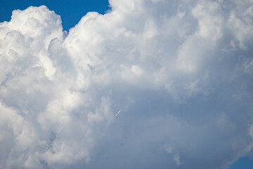 White airplane flying in front of a large dramatic cloud