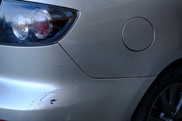 Obraz na płótnie Canvas Scratched back bumper on the grey metallic car. Closeup image of damaged back bumper on the car. Photo for the insurance company of a scratched car.