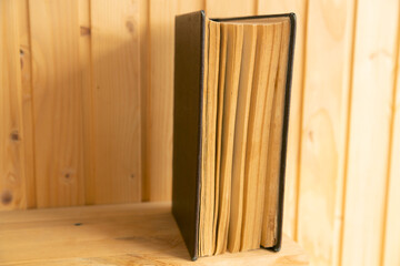 Open old book or textbook on a yellow wooden background. Symbol of the science of history. An old textbook of the last century in a brown leather binding on a shelf.