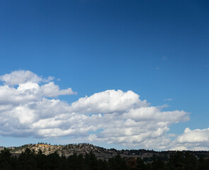 Dark blue sky with fluffy white clouds above mountains
