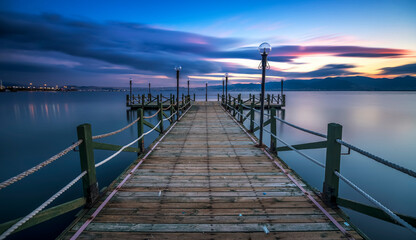 Naklejka na ściany i meble Long exposure photography, pier on a calm silky water with a beautiful colorful clouds and sunset on horizon as a background