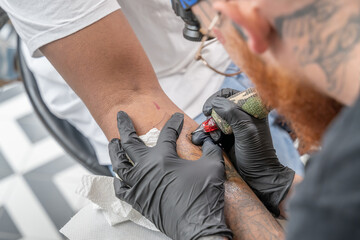 Tatoueur en train de tracer un tatouage sur un avant bras - obrazy, fototapety, plakaty