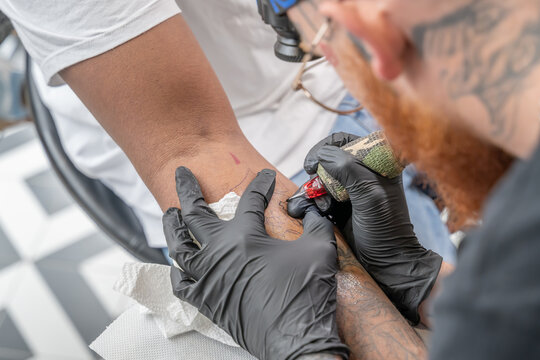 Tatoueur en train de tracer un tatouage sur un avant bras