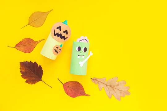 Halloween monster toy from toilet paper tube. Zombie and pumplin jack toys on yellow or orange background. Easy DIY craft idea for kids. Eco-friendly decoration, reuse recycle minimal trendy concept