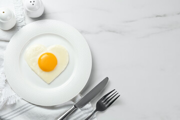 Heart shaped fried egg served on white marble table, flat lay. Space for text