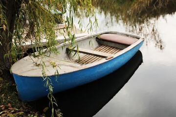 Naklejka na ściany i meble Light blue wooden boat on lake near pier