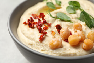 Tasty hummus with garnish in bowl on grey background, closeup