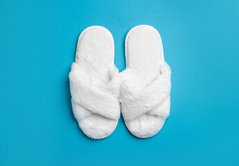 Pair of soft fluffy slippers on blue background, top view