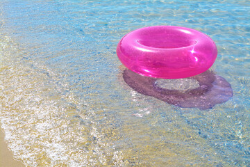 Bright inflatable ring on sandy beach near sea. Space for text
