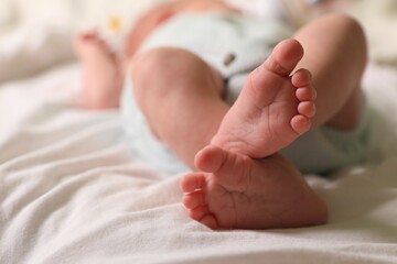 Cute newborn baby lying on bed, closeup of legs. Space for text