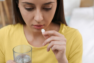 Young woman taking abortion pill on blurred background, closeup