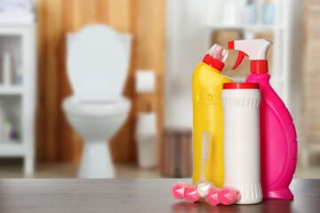 Different toilet cleaning supplies on wooden table in bathroom, space for text