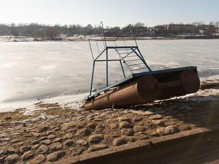 Small pontoon boat with iron construction on the paved shore