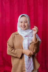 Portrait of cheerful beautiful Asian Woman in casual shirt. Beautiful Muslim Girl. Beautiful asian muslim female model posing in studio on red background.