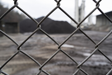 Wire fence with a defocused natural stone pile from an asphalt company in the background
