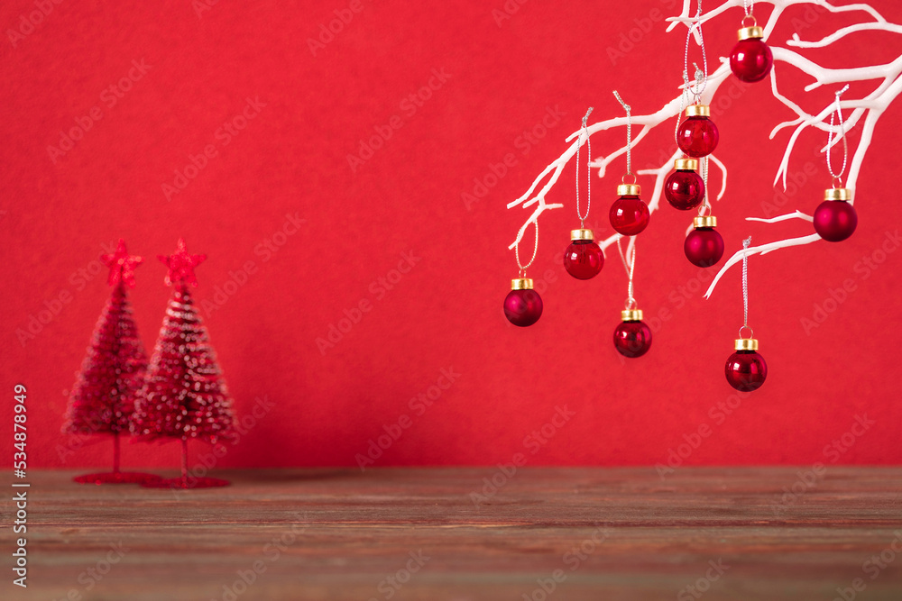 Poster merry christmas with xmas tree and bauble ball at vivid red wall at wooden table.copy space for addi